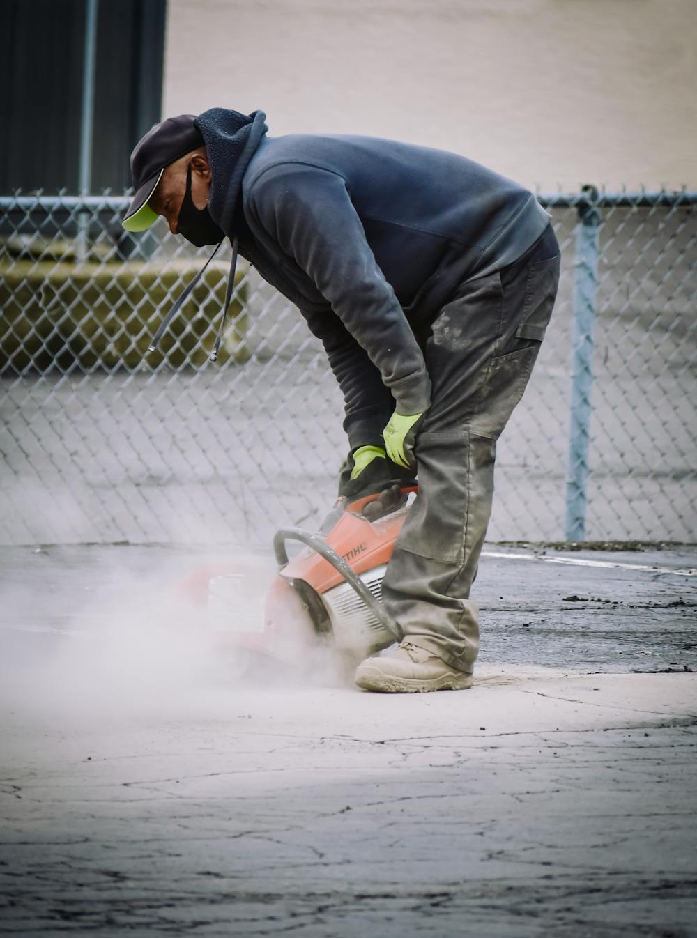 Construction worker grinding concrete surface in preparation for coating
